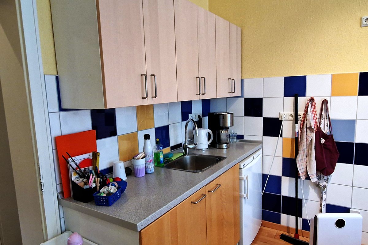 Küchenzeile mit Waschbecken, Vorratsschränken und bereitstehendem Bastelmaterial.