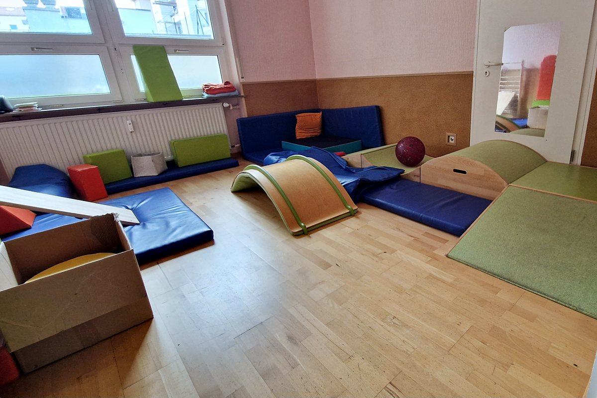 Tobezimmer mit freier Bewegungsfläche, Turnmatten, Wippe und Weichbodenelementen.