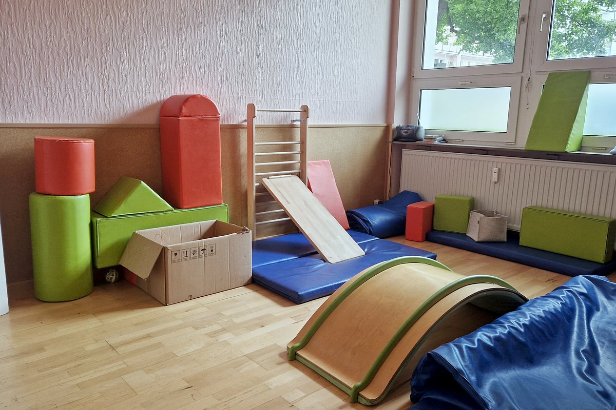 Sprossenwand mit Rutschbrett, Schaumstoffelementen und Matten im Tobezimmer.